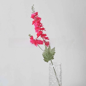 Macro detail of vibrant rose pink silk larkspur artificial flower in a glass vase