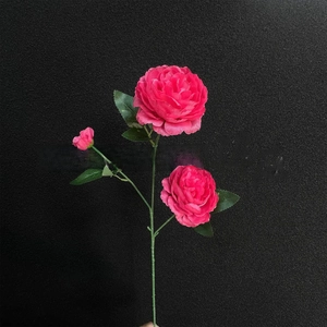 Close-up of artificial rose with two pink flower heads and a small bud on green stem