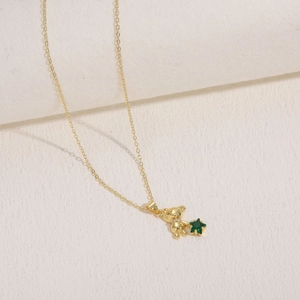 Close-up of golden bear necklace featuring a vibrant green star-shaped zircon stone