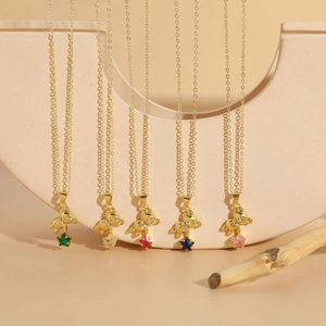 Close-up of five gold bear necklaces with colorful star-shaped zircon pendants on wood