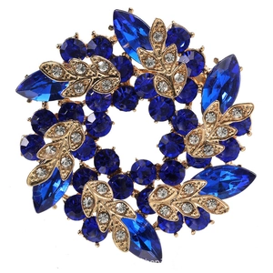 Macro detail of golden bauhinia brooch with deep blue and white crystals on white background