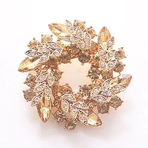 Macro detail of luxury champagne crystal wreath brooch with gold leaves and rhinestones
