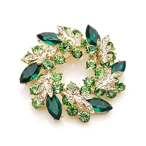 Macro detail of orchid wreath brooch featuring green crystals and gold plating