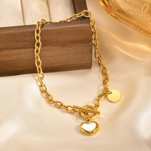Detailed view of a gold chain bracelet with OT clasp and shell heart pendant