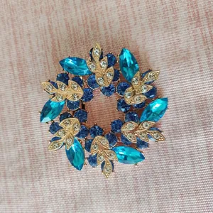 Close-up of golden floral wreath brooch with deep blue and turquoise gemstones