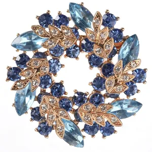 Detailed view of round garland brooch with blue crystals and gold leaf accents