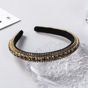 Detail of grey rhinestones on black velvet headband with golden metal settings
