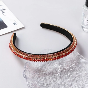 Macro detail of luxury red rhinestone headband with golden claw setting on velvet