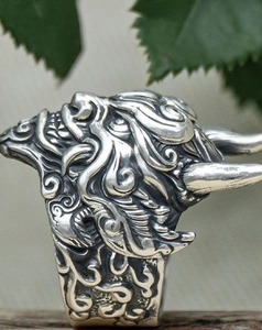 Macro side view of silver gothic ring with intricate mythological relief engraving