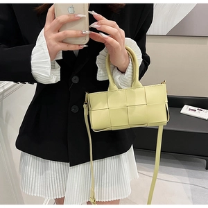 Dettaglio di una borsa a mano in pelle intrecciata giallo acceso con manico e tracolla