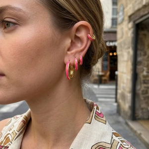Detail of 18K gold plated hoop earrings with pink enamel layered on a female model