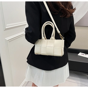 Dettaglio della borsa in pelle intrecciata bianca indossata con eleganti finiture dorate