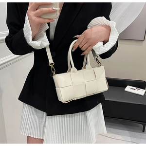 Dettaglio borsa a mano in pelle intrecciata bianca con hardware dorato e tracolla