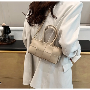 Dettaglio borsa in pelle intrecciata crema con doppi manici e tracolla staccabile