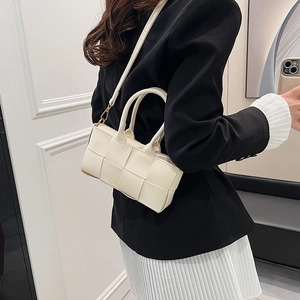 Borsa a mano bianca intrecciata con tracolla indossata da una modella elegante