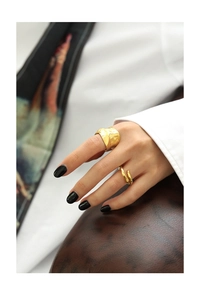 Close-up of gold irregular textured ring and thin cross-over ring set on model finger
