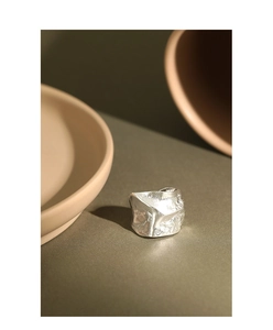 Macro detail of S925 sterling silver ring with irregular crumpled texture on green surface