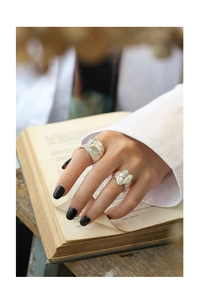 Close-up of irregular textured S925 sterling silver rings on a hand flipping a book