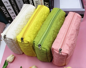 Detailed view of quilted floral cosmetic bags in multiple pastel macaron colors