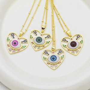 Pendenti a cuore Evil Eye dorati con zirconi colorati presentati in un piatto di ceramica