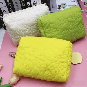 Detail of floral quilted cosmetic bags in white, yellow, and green with zipper closure