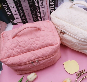 Macro view of floral quilted makeup bag with durable zipper and top handle detail