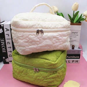 Detail of quilted floral makeup bags in cream and green colors with double zippers