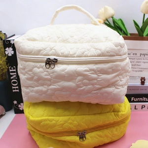 Quilted floral cosmetic bags in cream and yellow colors with portable top handles