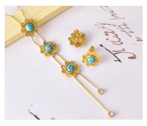Detailset aus goldener Blumenhalskette und Türkis-Ohrringen auf künstlerischem Grund