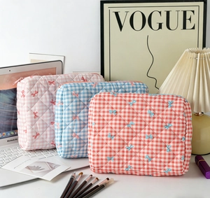 Close-up of three quilted checkered cosmetic bags with bow embroidery and zip closure