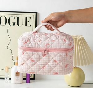 Detailed close-up of pink checkered quilted cosmetic bag with cute bow embroidery