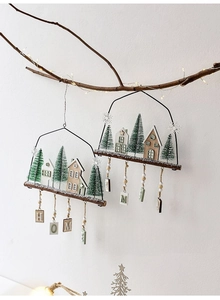 Detail of Nordic wooden Christmas house hanging ornament with HOME blocks on a lit branch