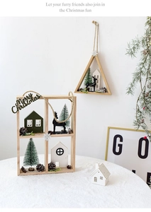 Close-up of Nordic wooden Christmas shelf with miniature house, deer and pine cones