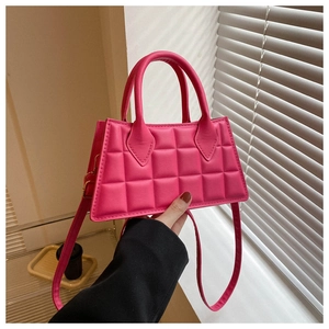 Gros plan du sac bandoulière rose fuchsia avec texture matelassée et détails dorés