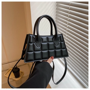 Détail d'un sac à main noir en similicuir matelassé avec poignées et bandoulière chic