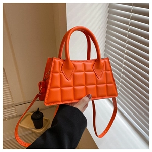 Détail du sac à main orange matelassé avec doubles poignées et une bandoulière