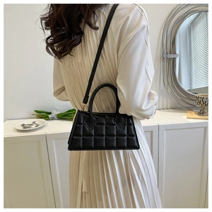 Sac à bandoulière en PU noir matelassé porté par un mannequin dans un décor épuré
