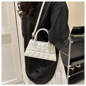 Détail d'un sac carré blanc matelassé montrant la poignée ronde et la texture fine