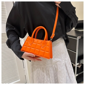Gros plan d'un mini sac à main matelassé orange vif avec des ferrures dorées