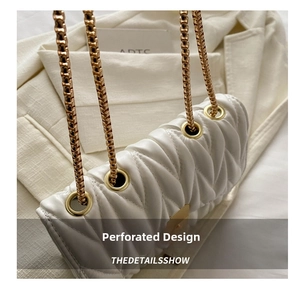 Close-up of V-shaped quilted white shoulder bag with golden chain and eyelet details
