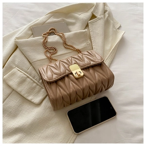 Close-up of brown quilted shoulder bag with gold twist lock and metal chain strap