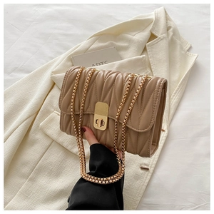 Detailed macro of pleated quilted texture and golden metal lock on chic chain bag