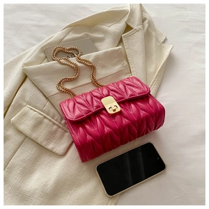 Detail of fuchsia quilted shoulder bag with V-shaped texture and gold chain strap