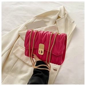 Detail of rose pink quilted crossbody bag with gold metal lock and elegant chain strap