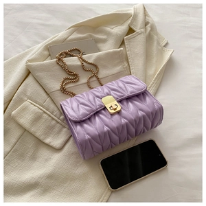 Detail of purple crossbody bag with V-shaped quilting and golden metal chain strap