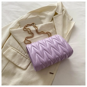 Detail of light purple quilted bag with gold chain strap on stylish beige blazer