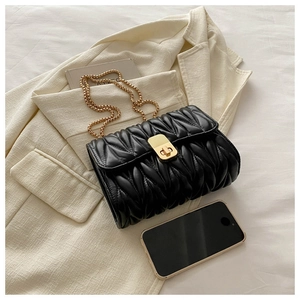 Close-up of black pleated faux leather bag with gold chain strap and metal clasp