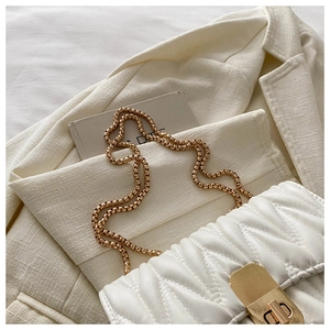 Detailed close-up of white quilted chain shoulder bag with gold metal twist lock