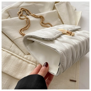 Detail of cream quilted crossbody bag with gold chain and rectangular twist lock closure