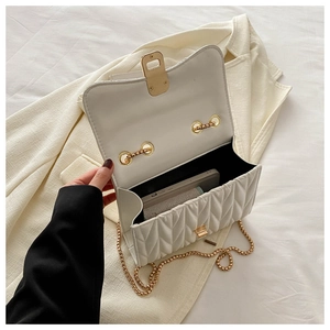 Close-up of white quilted chain bag with gold hardware and interior compartment